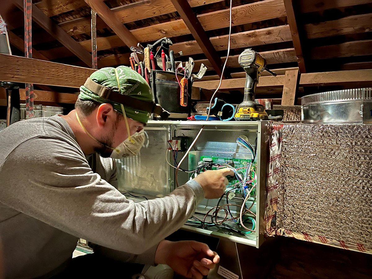 A Pon Air technician working inside an attic furnace cabinet.